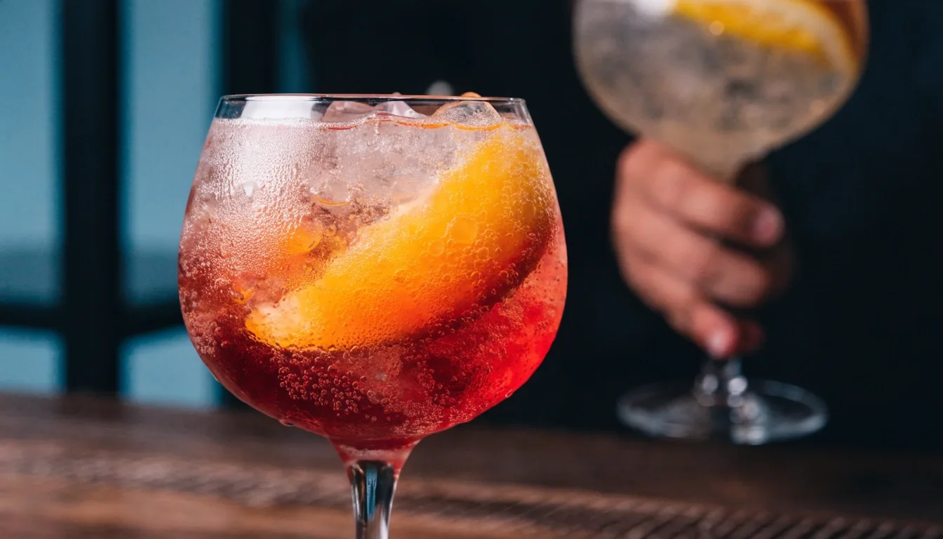 A bubbling mocktail over crushed ice in a coupe glass on a dark bar top